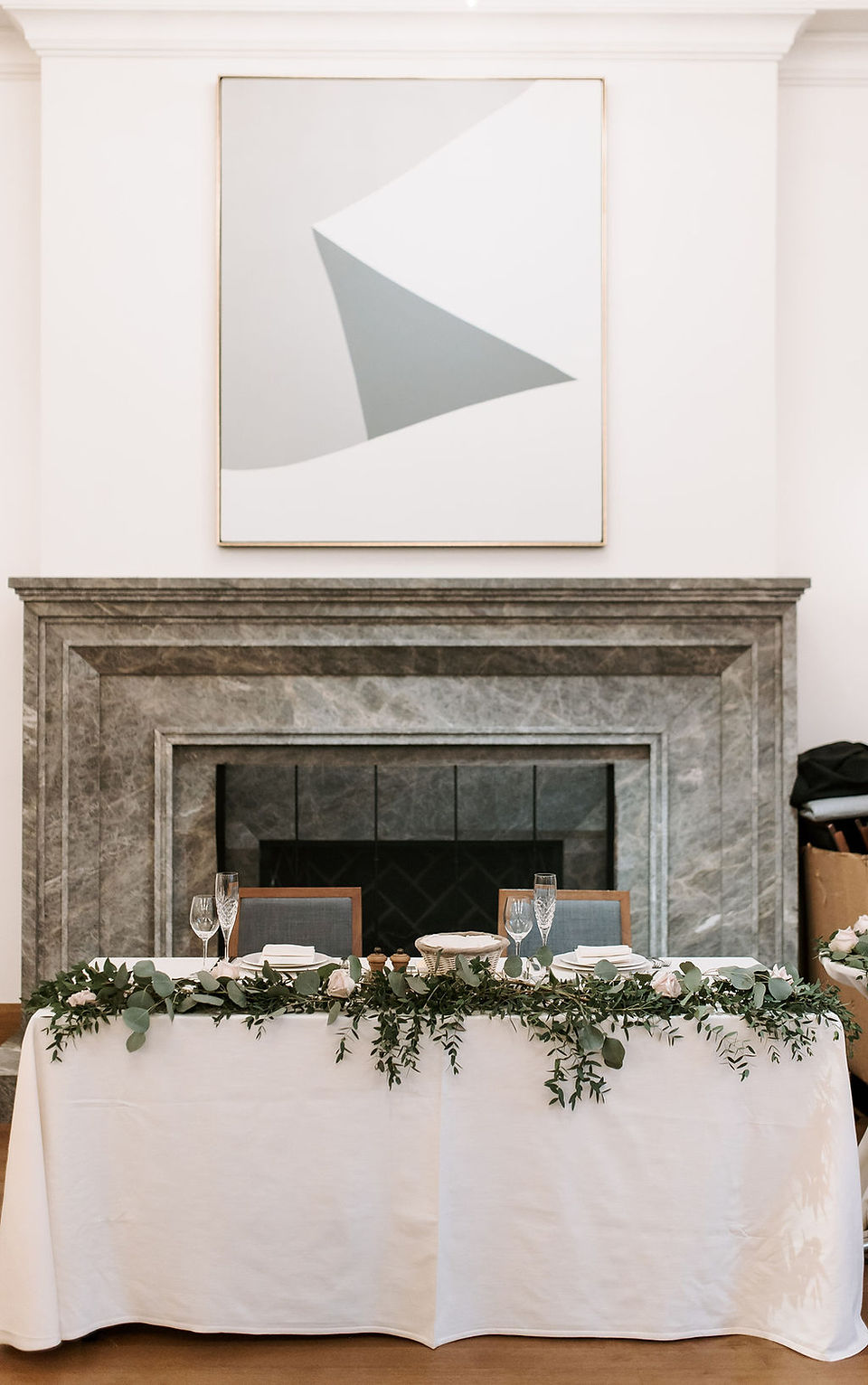 Wedding reception sweetheart table in front of a marble fireplace.