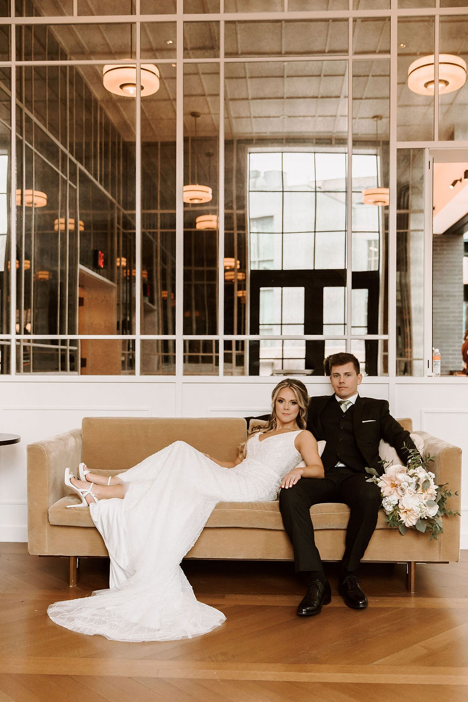 Bride and groom posing elegantly on a couch inside the Shinola Hotel in Detroit.