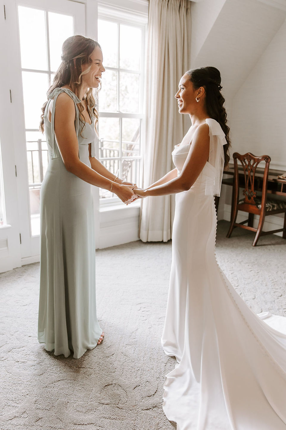 Bride and her sister holding hands after getting ready in the bridal suite.