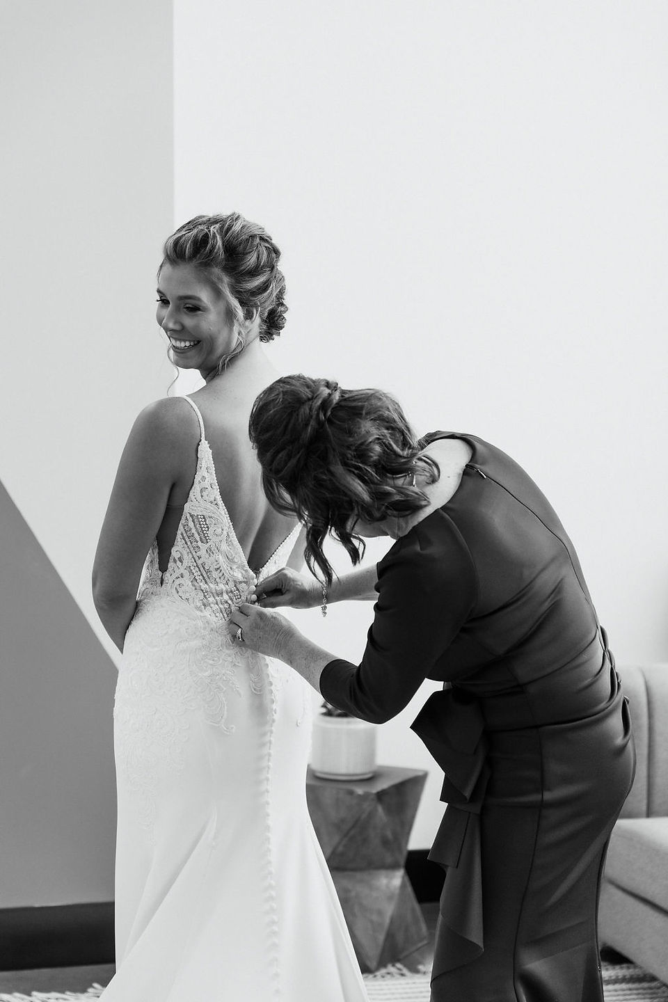 Bride getting her dress zipped up by her mother on her wedding day.