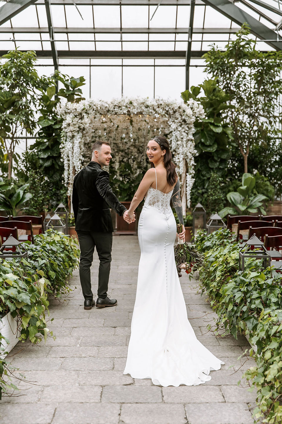 Groom leading bride towards the altar at the romantic Planterra Conservatory venue.