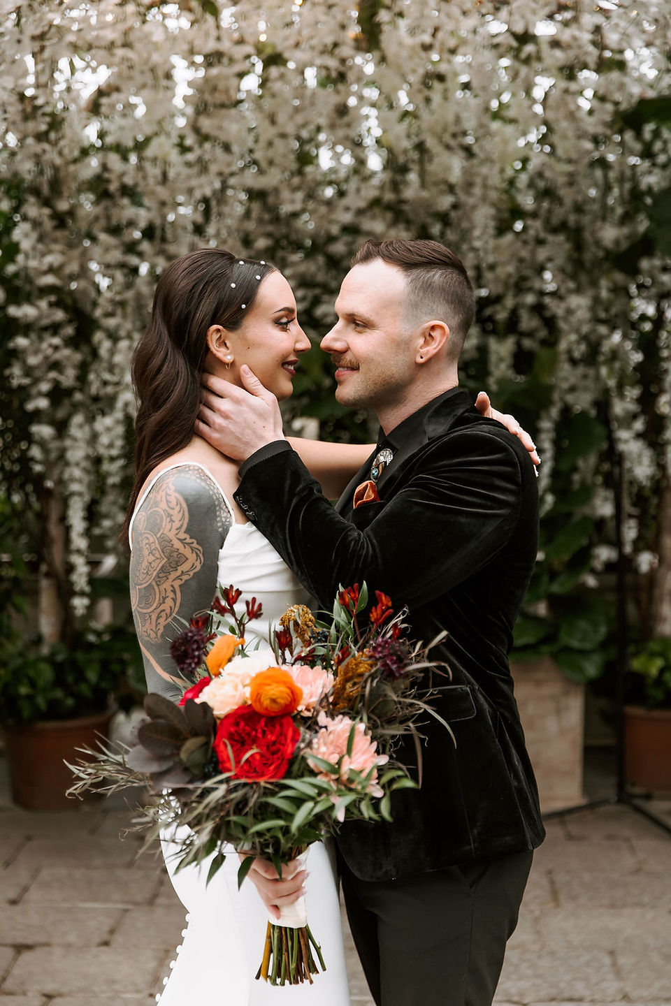 Bride and groom embracing and going in for a kiss while bride holds her bouquet.
