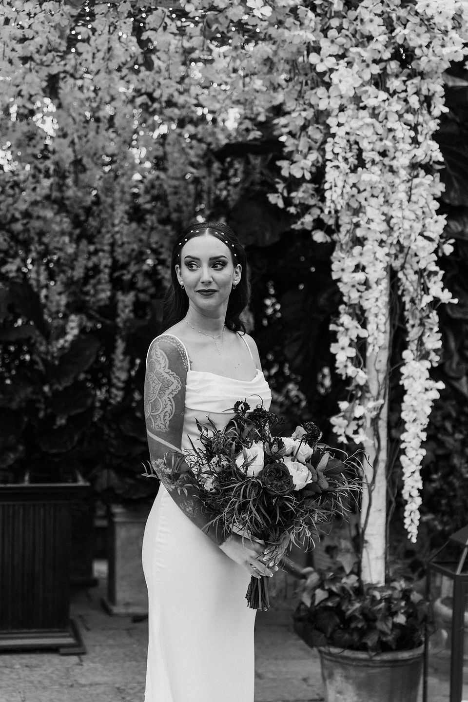 Black and white bridal portrait standing in front of a floral altar.