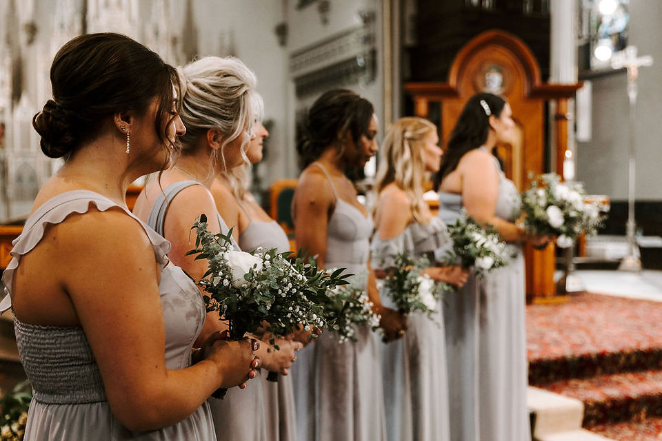 Bridesmaids standing next to the altar at Catholic wedding ceremony at Cathedral of St. Andrew in Grand Rapids.