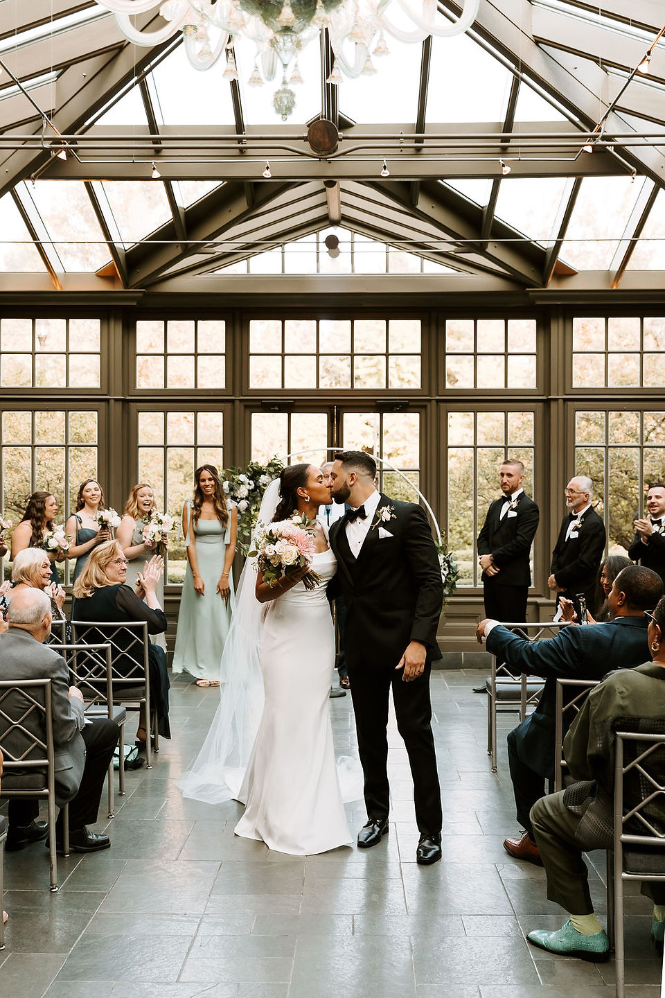 Bride and groom kiss during their recessional at the Royal Park Hotel Belgium Glass Conservatory.
