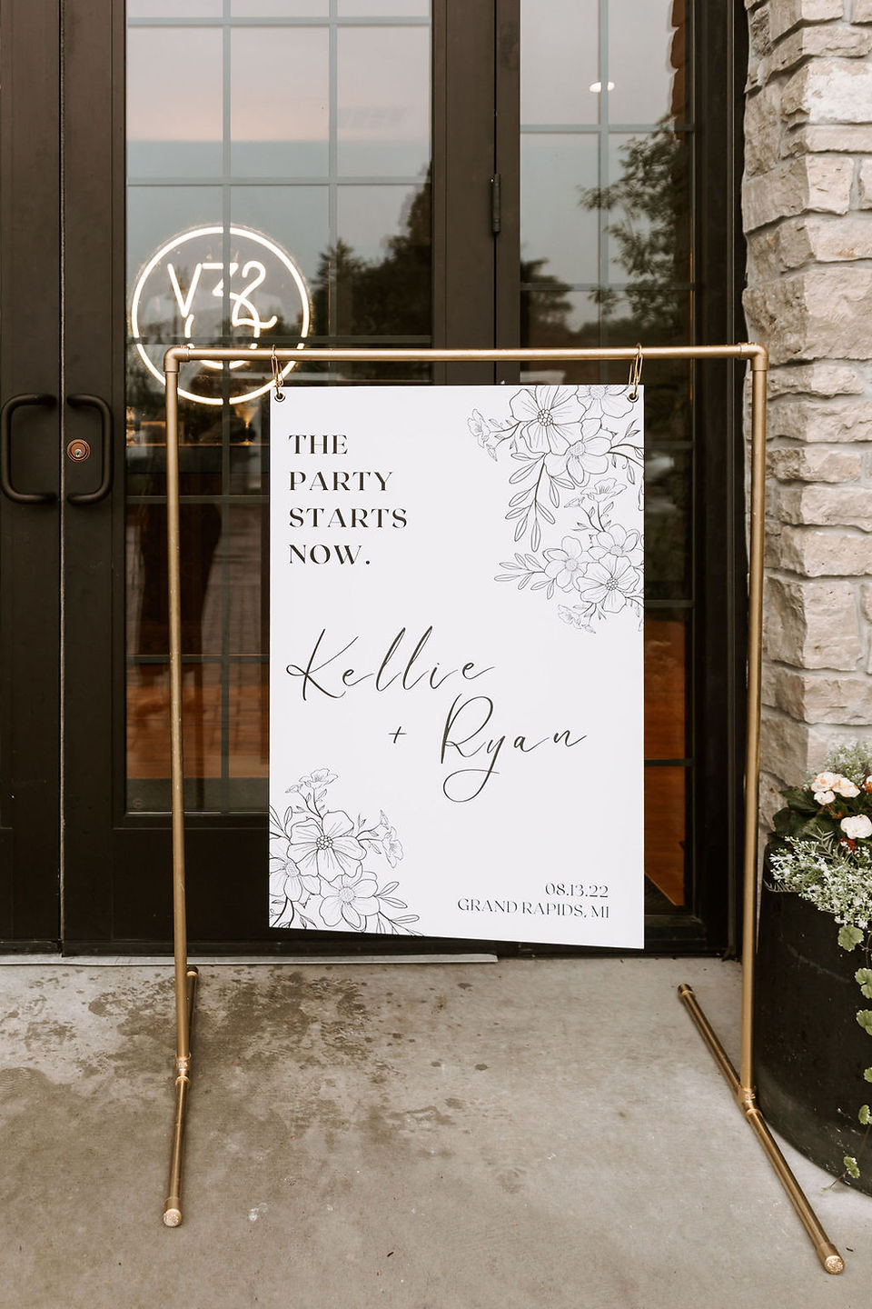 Modern white and black wedding welcome sign on a gold pipe stand.