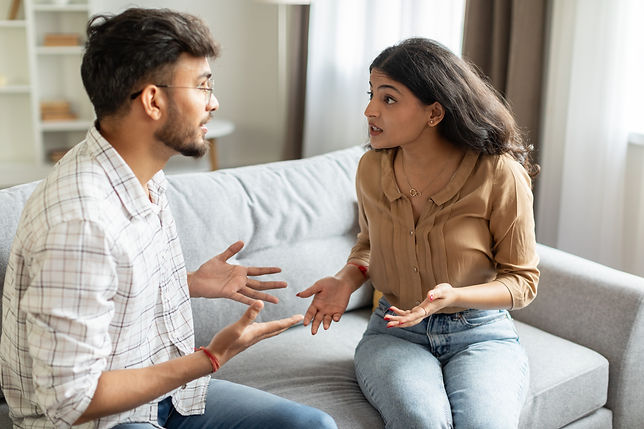 Angry indian couple having quarrel experiencing crisis in relationship, sitting on sofa an