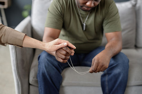 Close up of struggling army veteran holding dog tags necklace in therapy session with psyc
