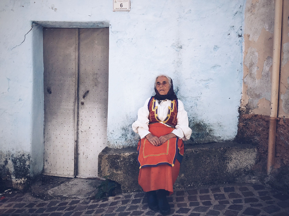 woman sat in a dress on the streets of Desulo