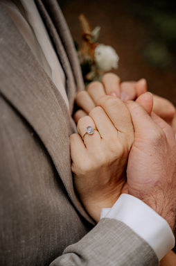 Nahaufnahme von Händen eines Brautpaars, die ihre Eheringe zeigen.