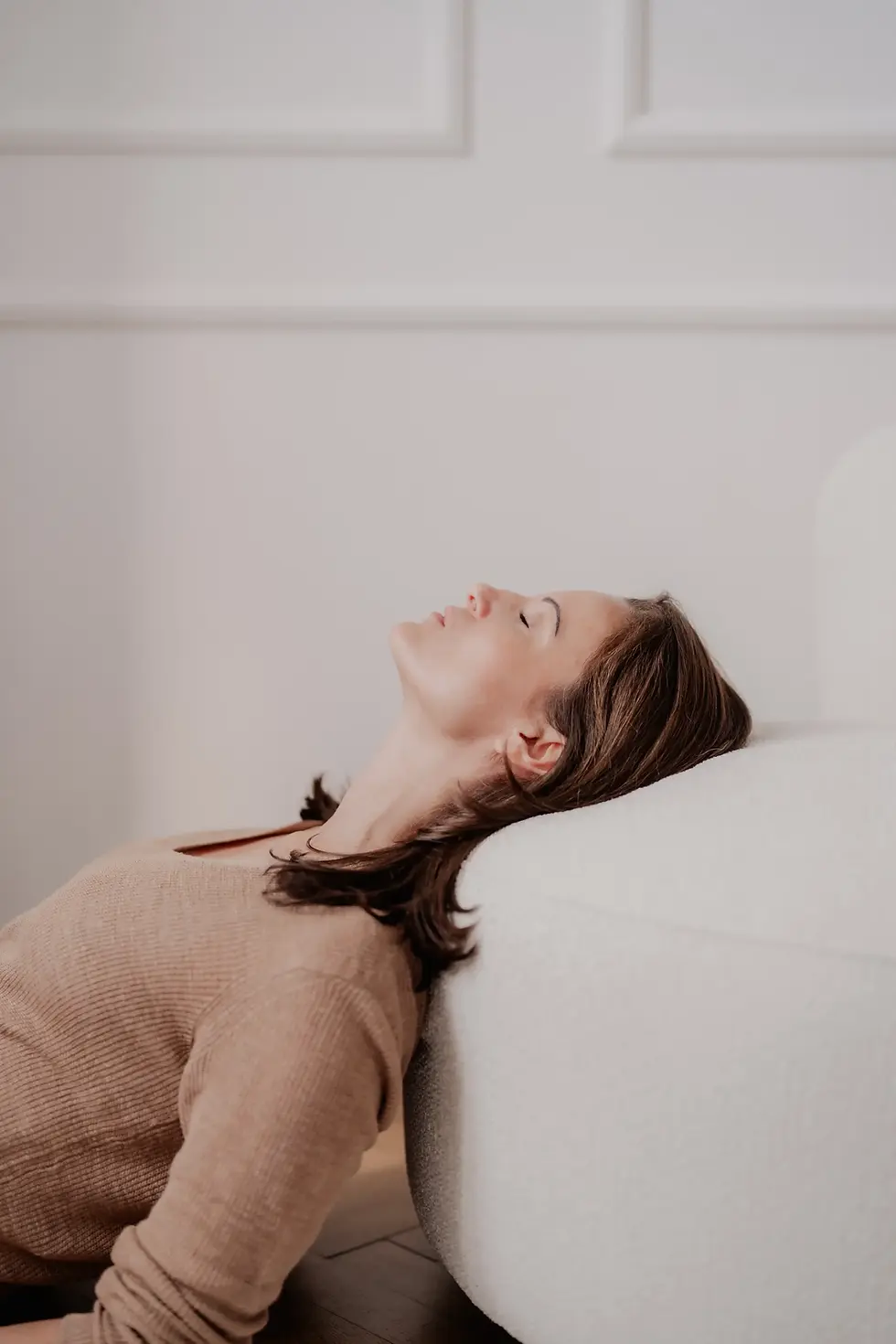 Lifecoach Anita Geißler lehnt an einem Sofa mit geschlossenen Augen während Achtsamkeitsübung in ihrem Mindset Coaching in Graz.
