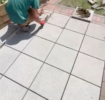 View of a man working on the floor tiling outside the house