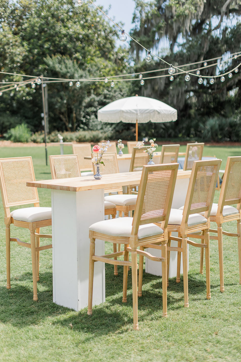 Outdoor Charleston wedding reception tables with gold chairs and floral centerpieces.