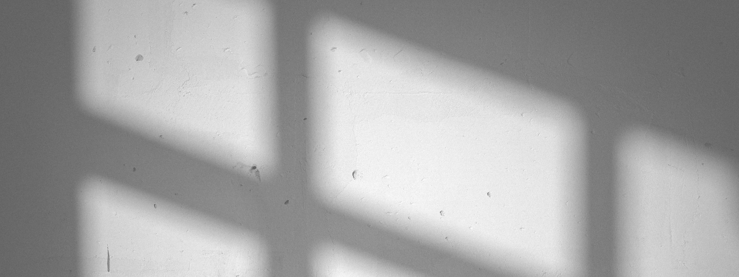 A window grid cast in light on a plain wall.