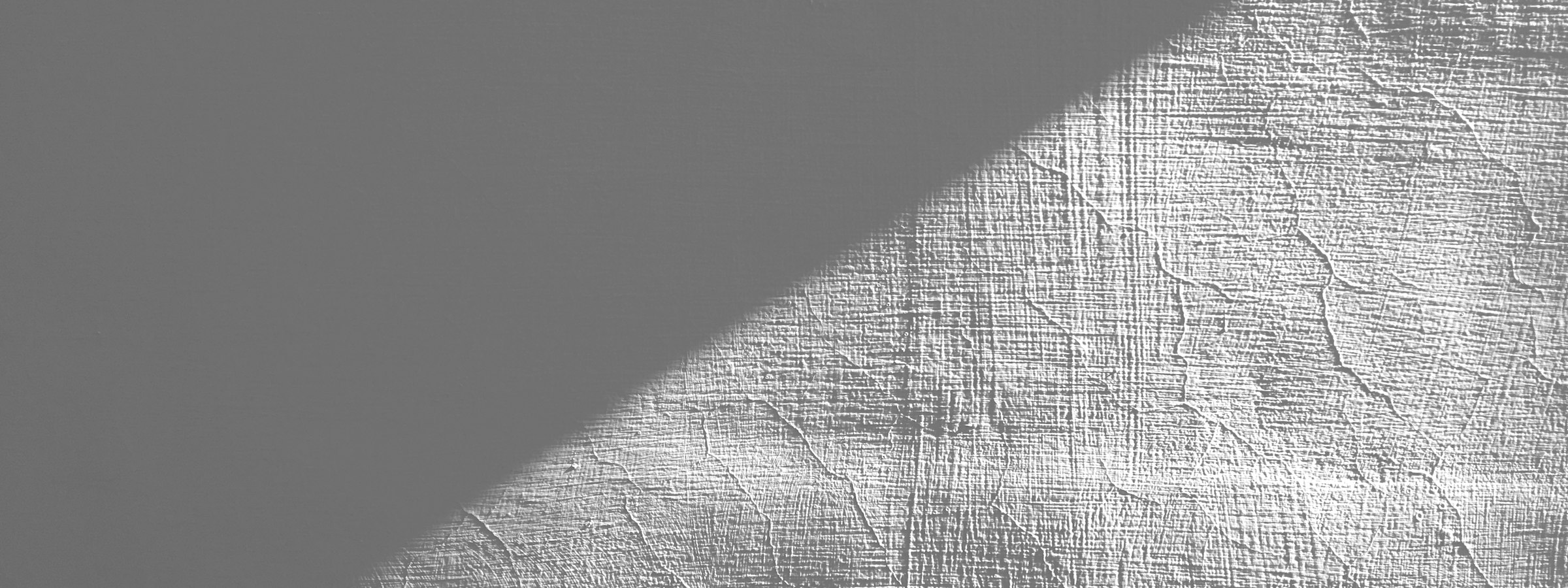 A single diagonal of light on a textured wall.