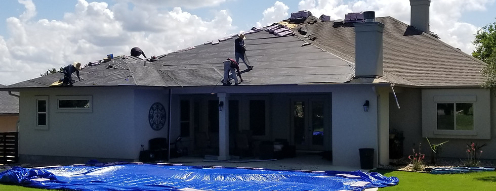 Residential roof replacement in progress with roofing crew installing new shingles on a single family home.