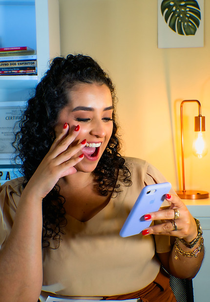 Eduarda com um celular na mão e sorrindo FELIZ.