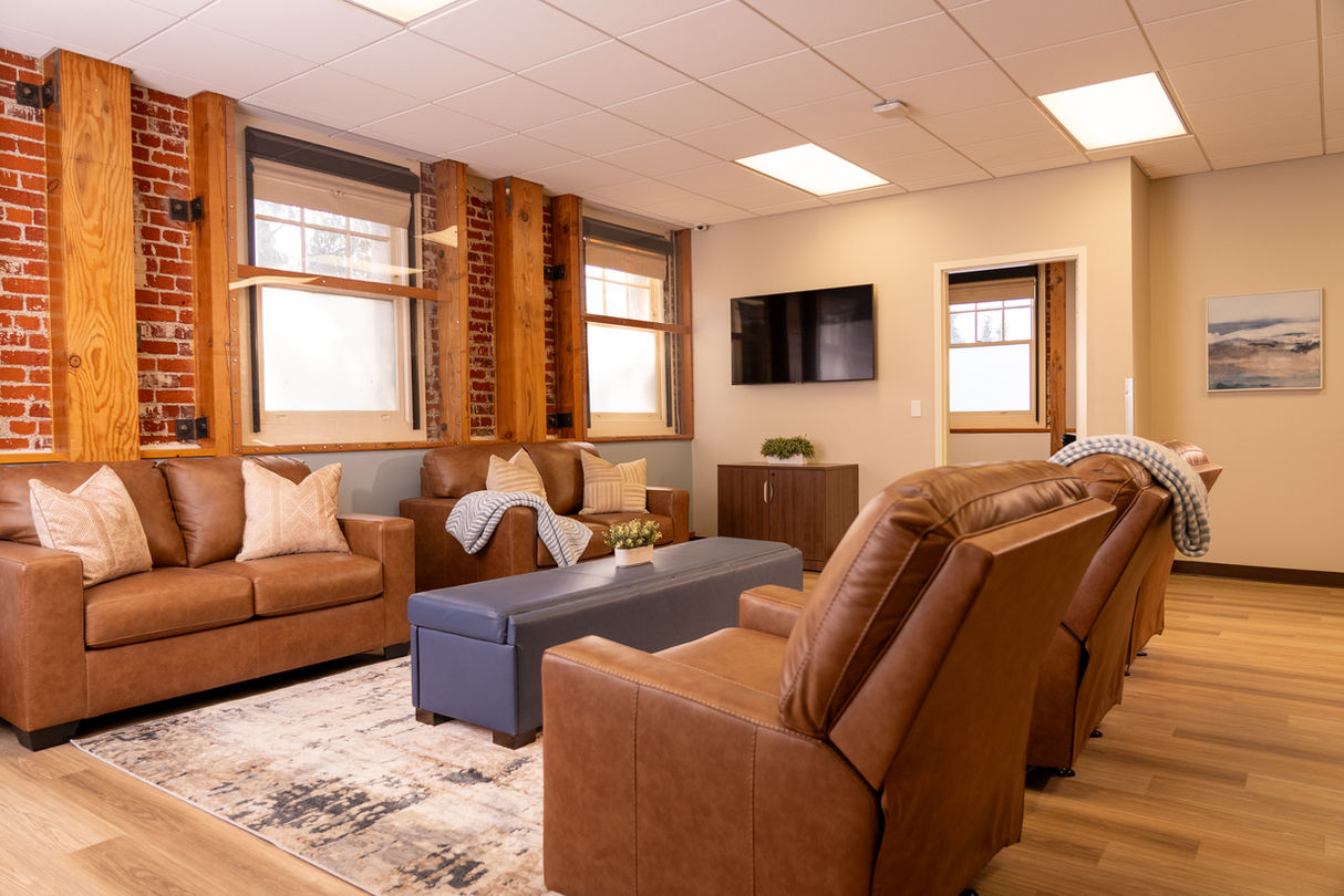 Living room TV area with brown leather couches and recliners.