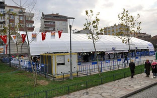 Een ijsbaan in een tent en een koelmachine buiten de tent, gefotografeerd vanaf de buitenkant.
