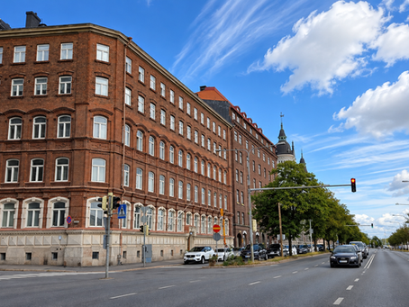 Punatiilisiä kerrostaloja kaupunkikadun varrella sinisen taivaan alla.