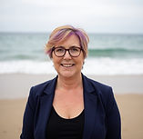 whispy hair, black top blue blazer blurry beach.jpeg