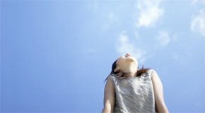 Woman looking up at bright blue sky