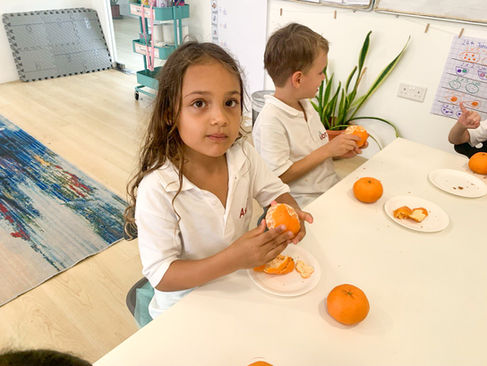 Students are eating oranges to celebrate Lunar New Year at Astor International School