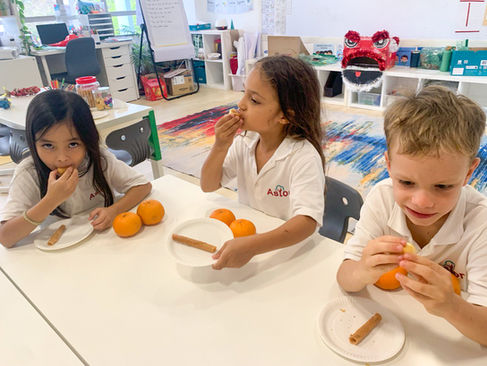 Students are eating oranges to celebrate Lunar New Year at Astor International School