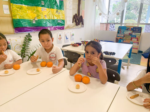 Students are eating oranges to celebrate Lunar New Year at Astor International School