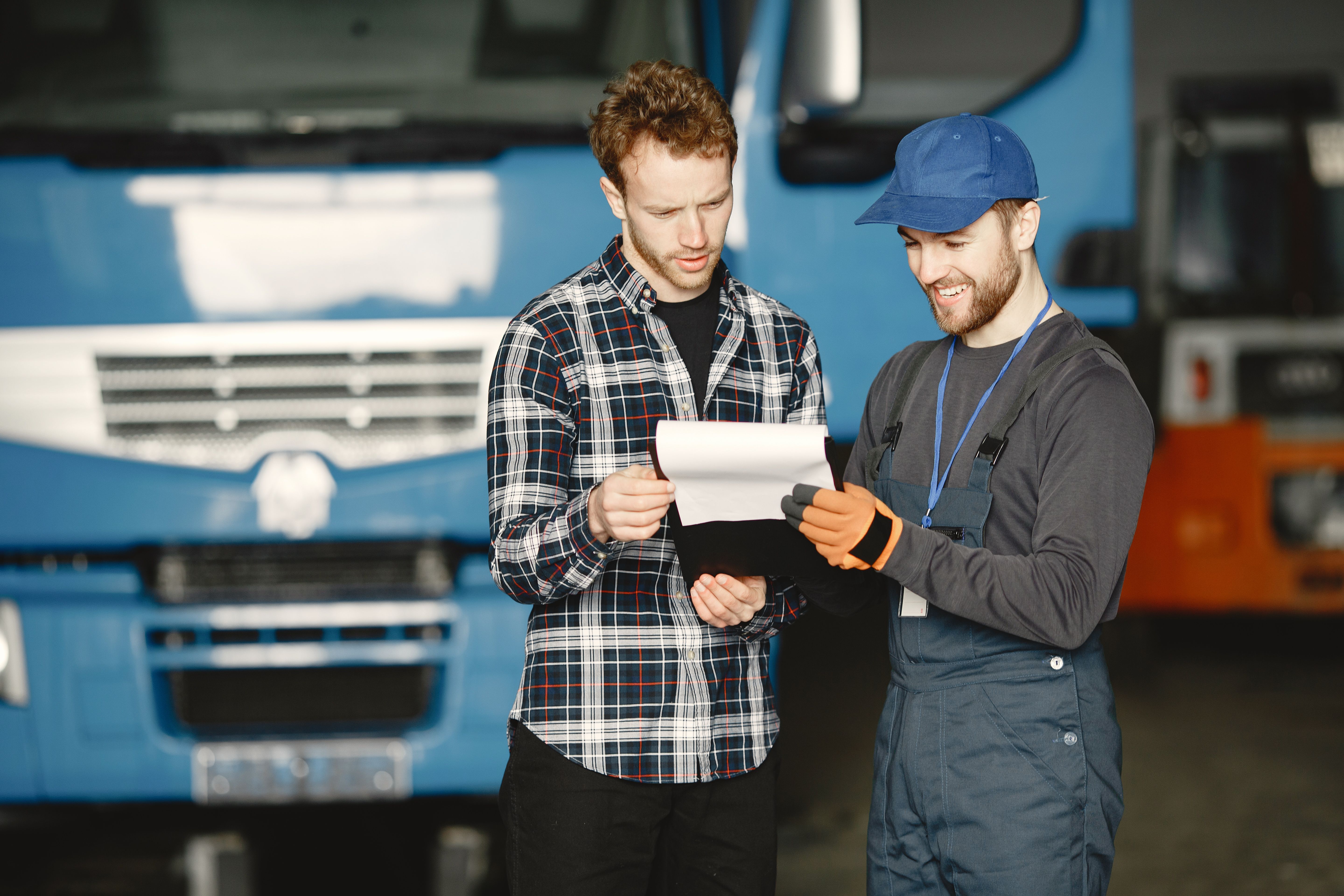 Two team members reviewing a work order together in front of a fleet truck