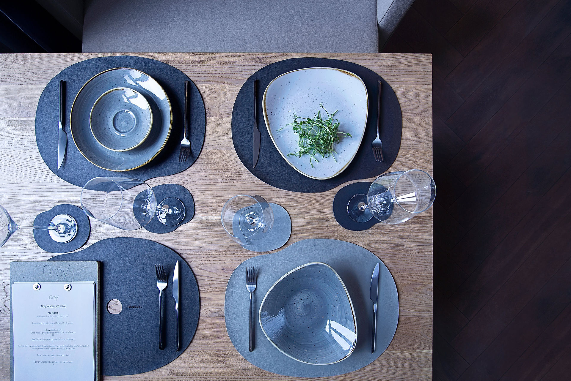 "Milestones" Table mat and Coaster with plates, utensils and wine glasses on a wooden table