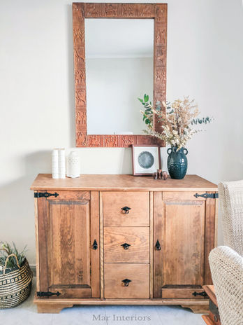 Wooden sideboard styled with decorative accessories and mirror in a refreshed living space