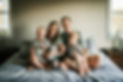 Family with newborn sitting on bed