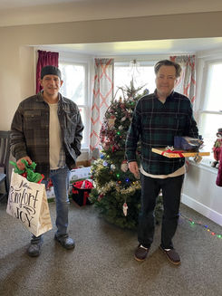 Two men with gifts by Christmas tree