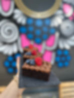 Schokoladen-Brownie mit cremigem Schokofrosting, garniert mit frischen Himbeeren und Blaubeeren, serviert im Kira's