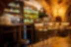 Scaffale di bottiglie e specchio dorato con divani in pelle al The Race Club, mixology bar vicino al Colosseo