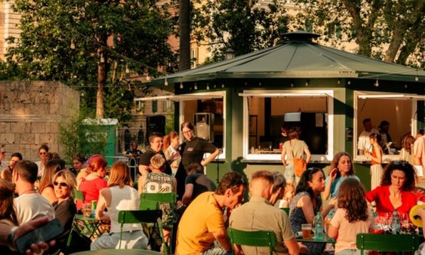 Tavoli all'aperto tra il verde durante un evento con dj set del Vinificio Roma
