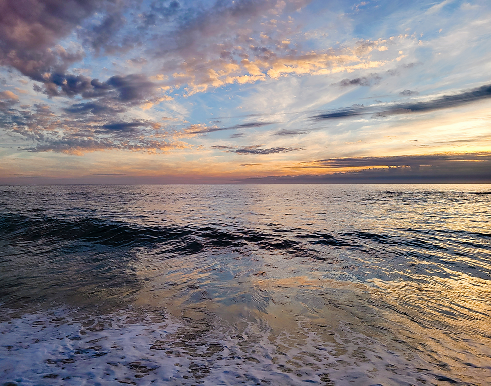 Beautiful ocean waves reflecting colorful sunset sky with wispy clouds