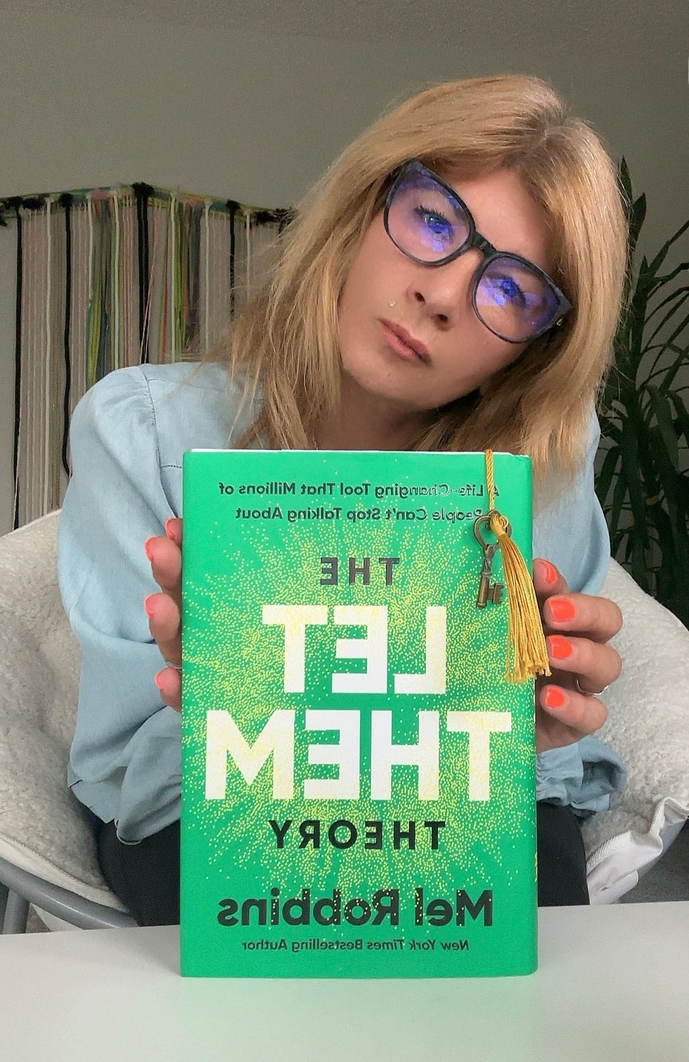 A person presenting "The Let Them Theory" by Mel Robbins, a book about embracing change and happiness.