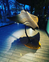 Sculpture de raie manta stylisée sur terrasse en bois la nuit.
