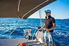 Capitán profesional al timón de un catamarán navegando por las aguas turquesas de Guna Yala, Panamá. Bolsa de empleo para tripulación en San Blas.