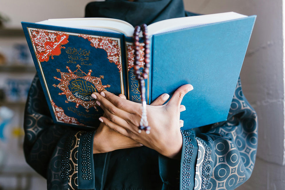 Person wearing a detailed robe holds an ornate blue book with Arabic text and a beaded tassel, creating a peaceful mood indoors. Blog about Spiritually Integrated Therapy. 