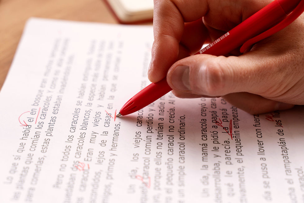 Hand with red pen marking a Spanish-language document on a desk, with circled and underlined words.
