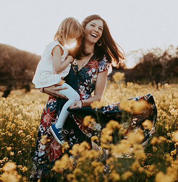 Elan Fayard of Azur Wines holding her child in a field of flowers