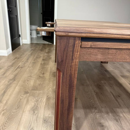 Close-up of custom walnut gaming table leg with contrasting inlay and built-in stainless cup holder by Chisel Woodworking in London, Ontario