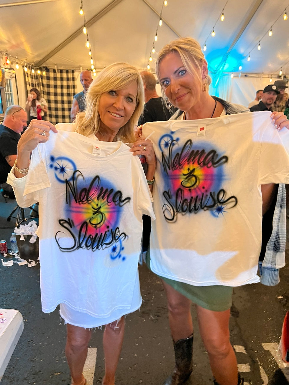 Two backstage guests displaying personalized airbrushed shirts at a Nashville music event