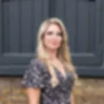 Woman with long blonde hair, glasses, and floral dress