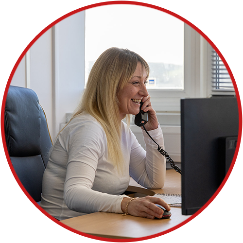 Smiling woman talking on phone, using computer in office.