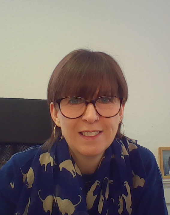 Smiling woman with short brown hair, glasses, blue animal-print scarf.