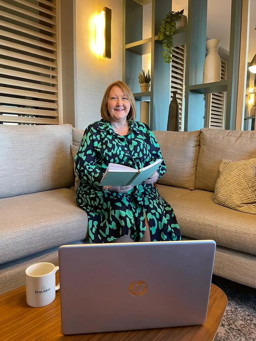 Smiling woman on couch with book, laptop, and coffee